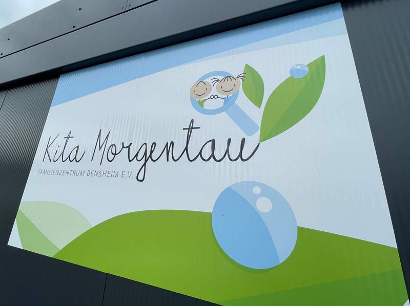 Schild mit Logo der Kita Morgentau im Außenbereich.