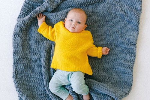 Ein Baby liegt auf einer Decke.