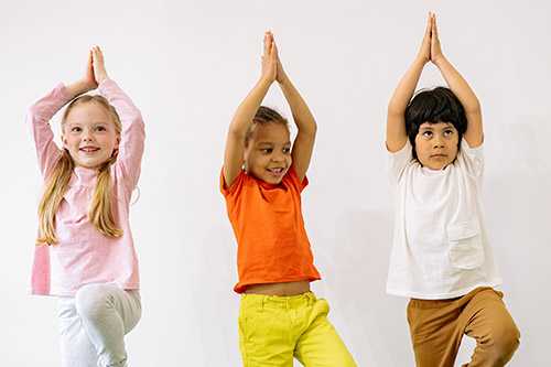 Drei Kinder machen Yoga.