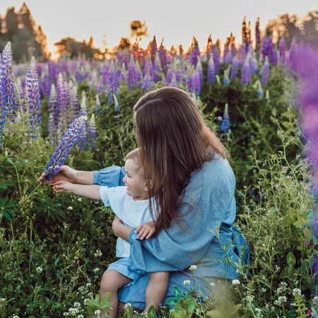 Mutter sitzt mit Baby in Blumenwiese