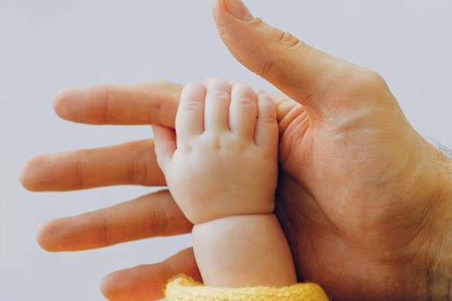 Babyhand greift nach Papas Hand.